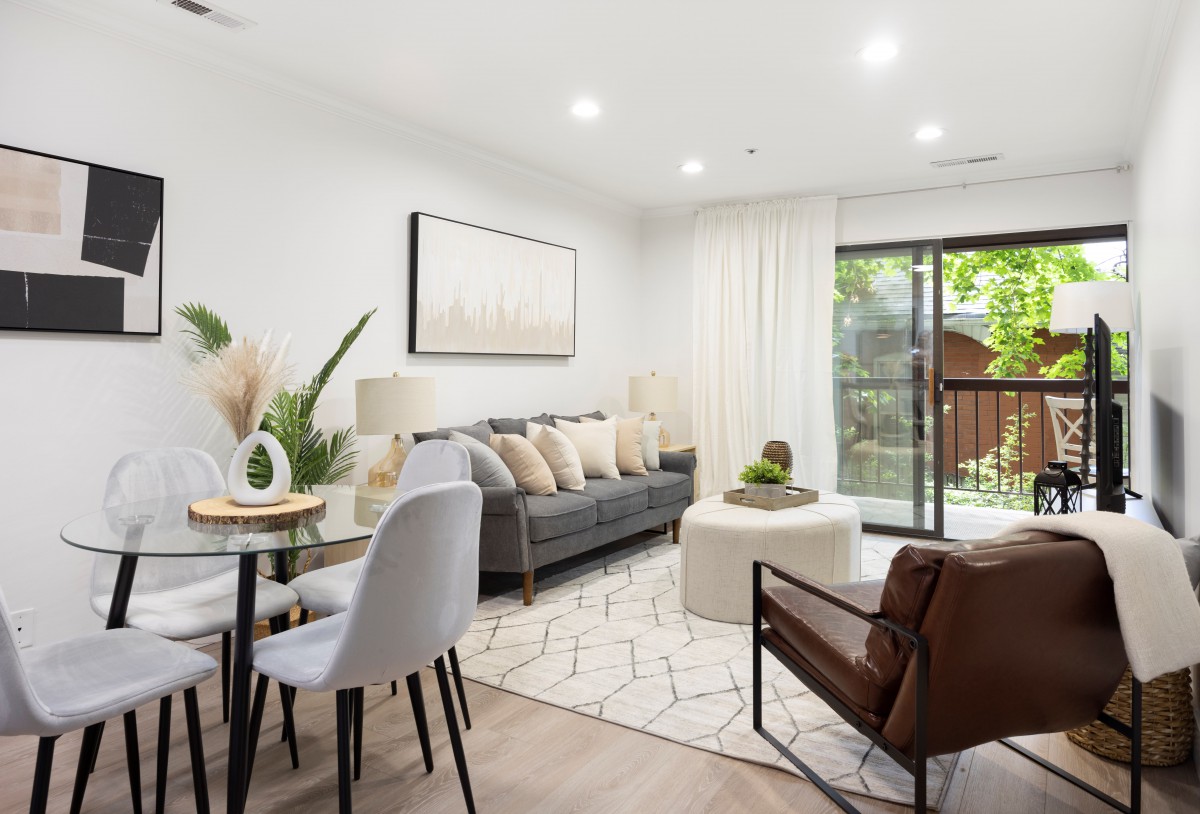 A modern and stylish living room featuring a comfortable sofa, dining area, and abundant natural light.