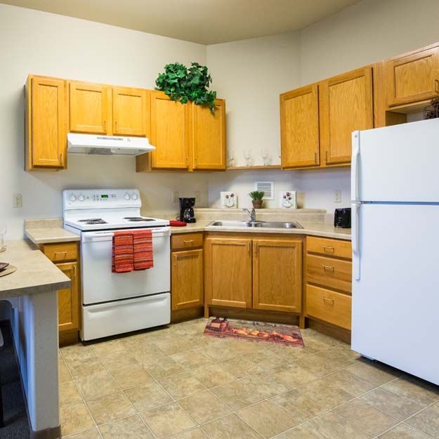 A cozy kitchen with wooden cabinets, a white refrigerator, and a stove.