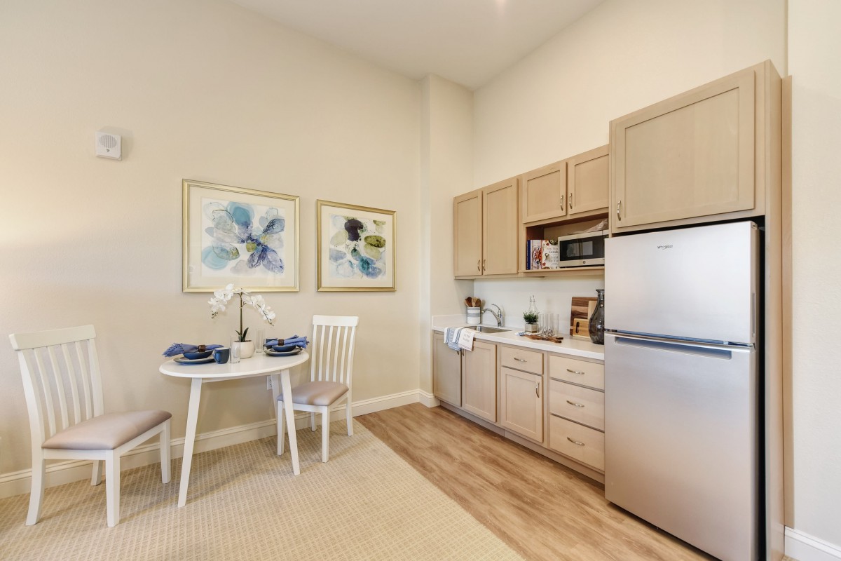 A cozy kitchen with a small dining area, featuring wooden cabinets and modern appliances.