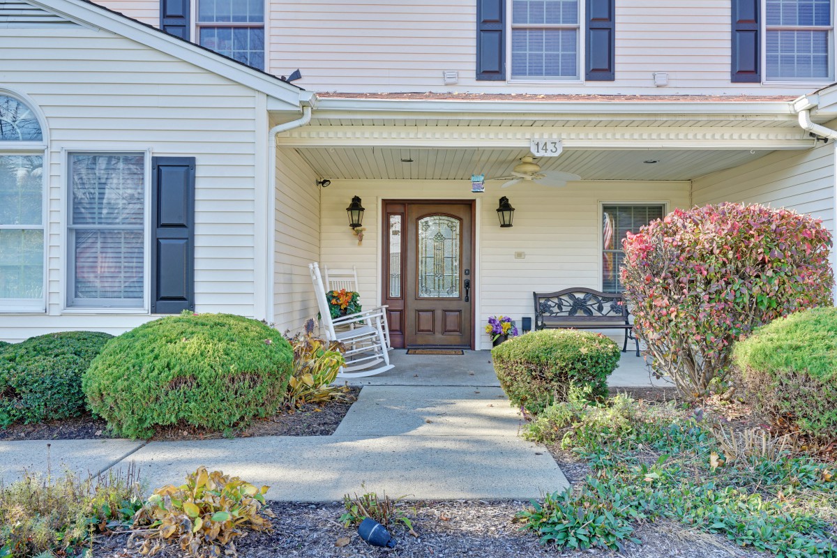 A welcoming front porch of a residential house with a rocking chair and landscaped walkway.