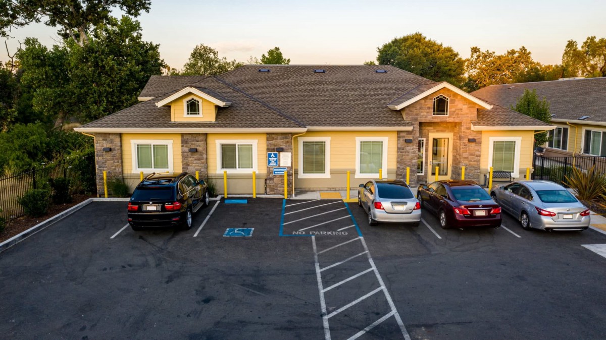 A suburban building with a parking lot at sunset, featuring parked cars and accessible spaces.