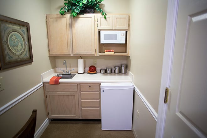 A compact kitchenette with wooden cabinets, a microwave, and a small refrigerator.