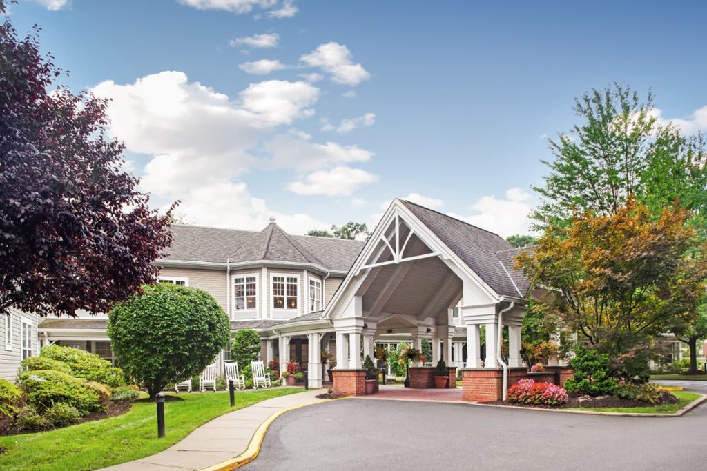 A scenic view of a hotel entrance with a covered driveway and landscaped surroundings.