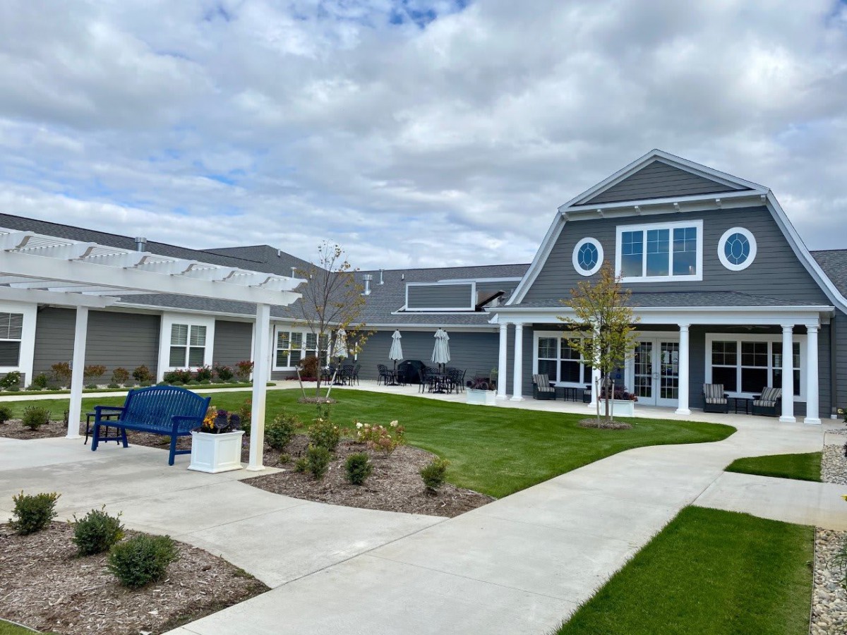 A modern building with a landscaped garden and pathway under a cloudy sky.