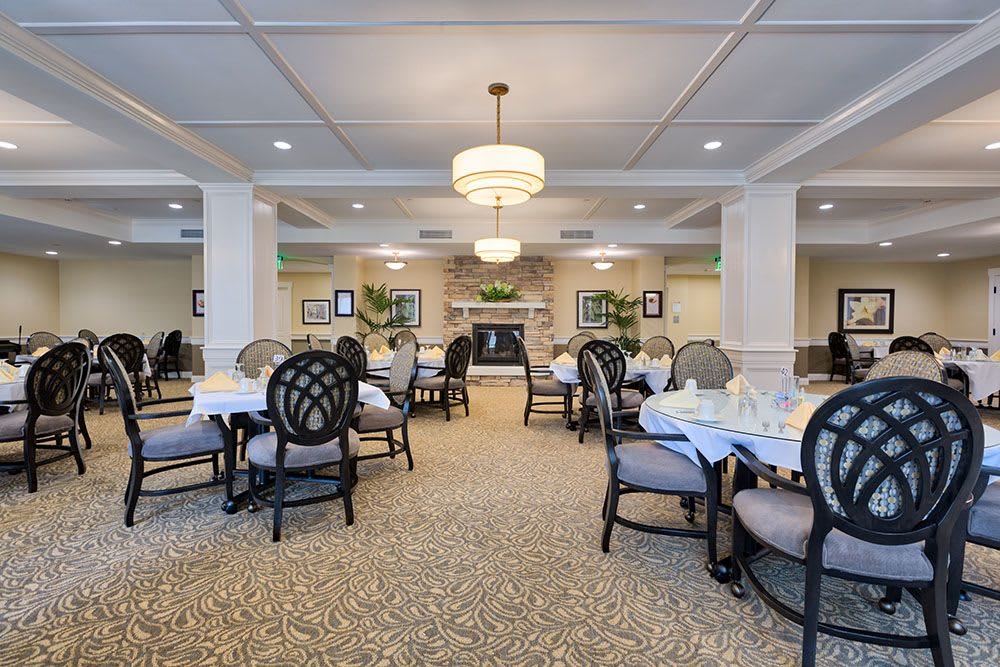 An elegantly designed dining room featuring neatly arranged tables and chairs, complemented by stylish chandeliers and tasteful decor.