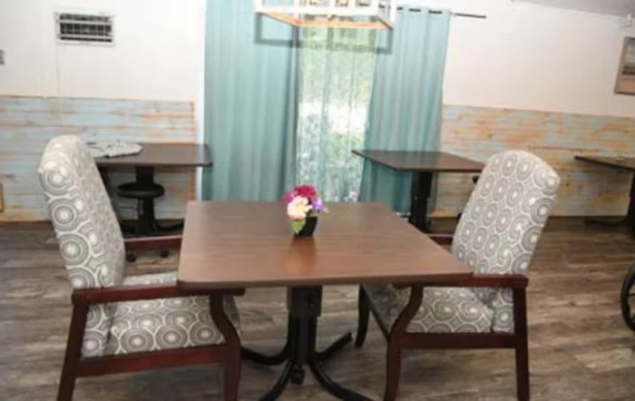 A cozy dining area featuring a wooden table with floral centerpiece and upholstered chairs.