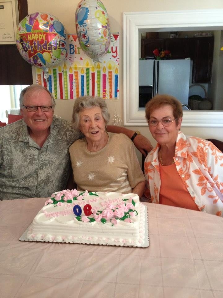 Elderly woman celebrating her birthday with cake and family.