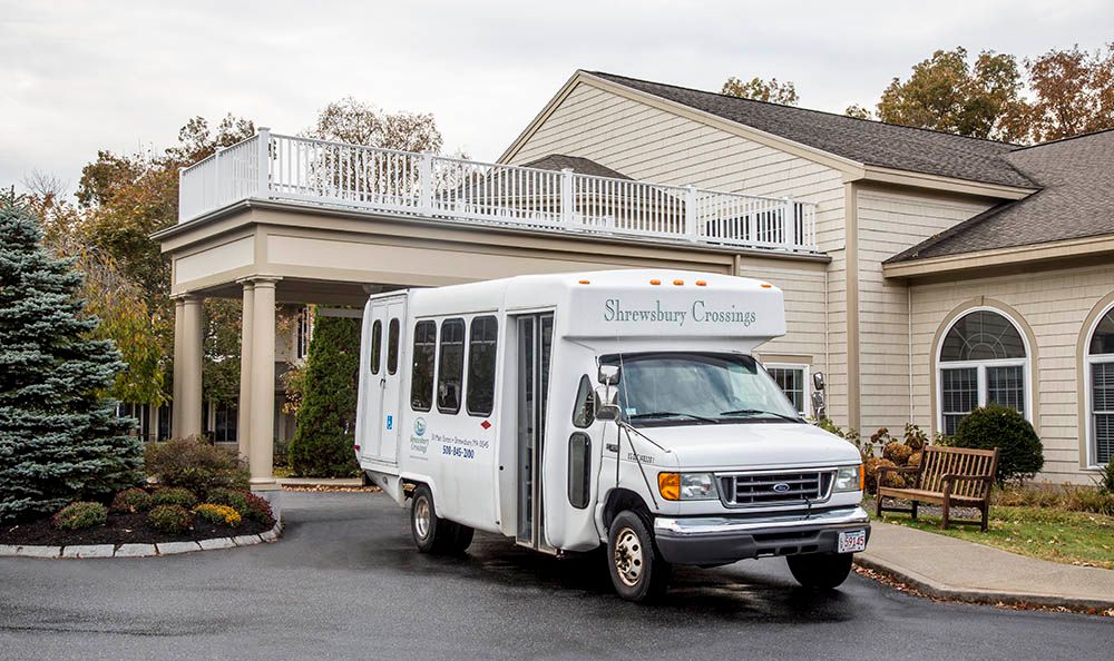 A shuttle bus parked in the driveway of a building.