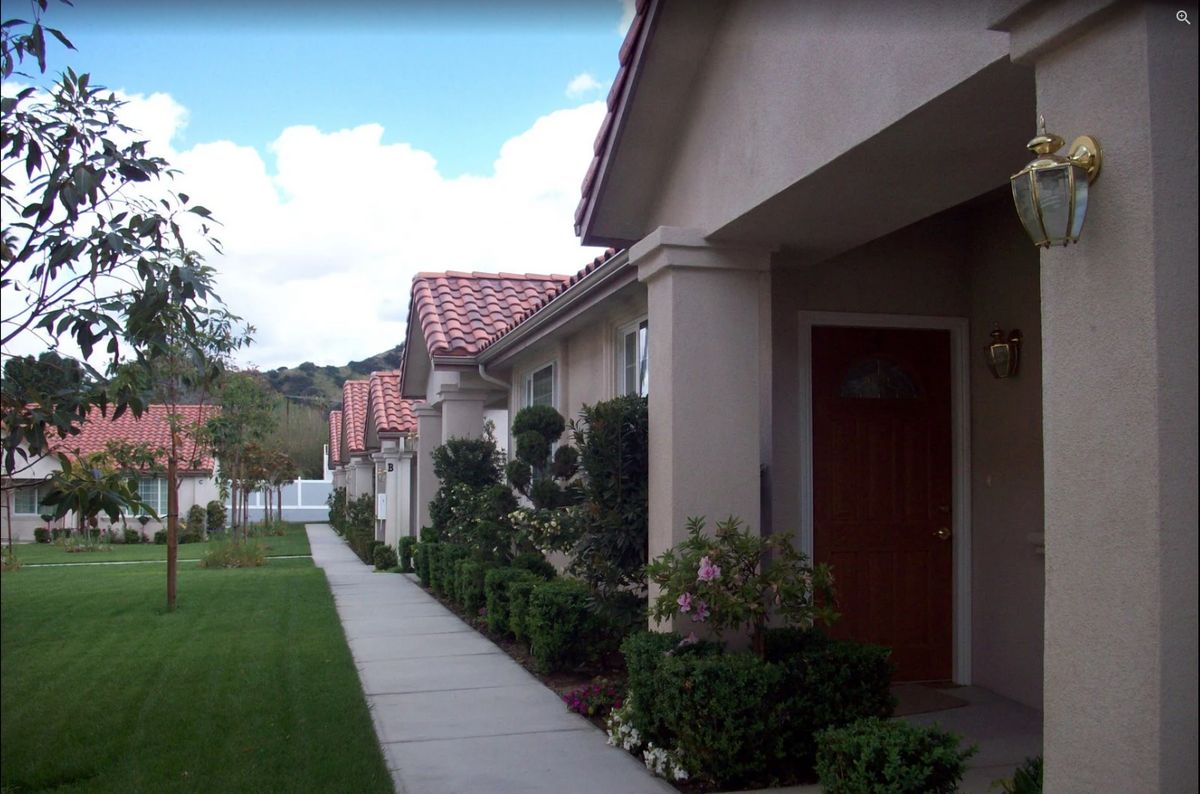 A row of suburban houses with well-maintained landscaping and a sidewalk.