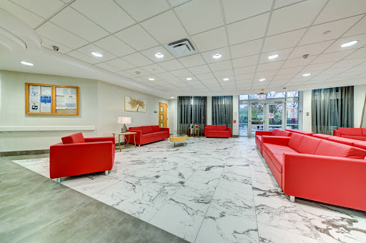 A spacious and modern lobby featuring red sofas and a marble floor.