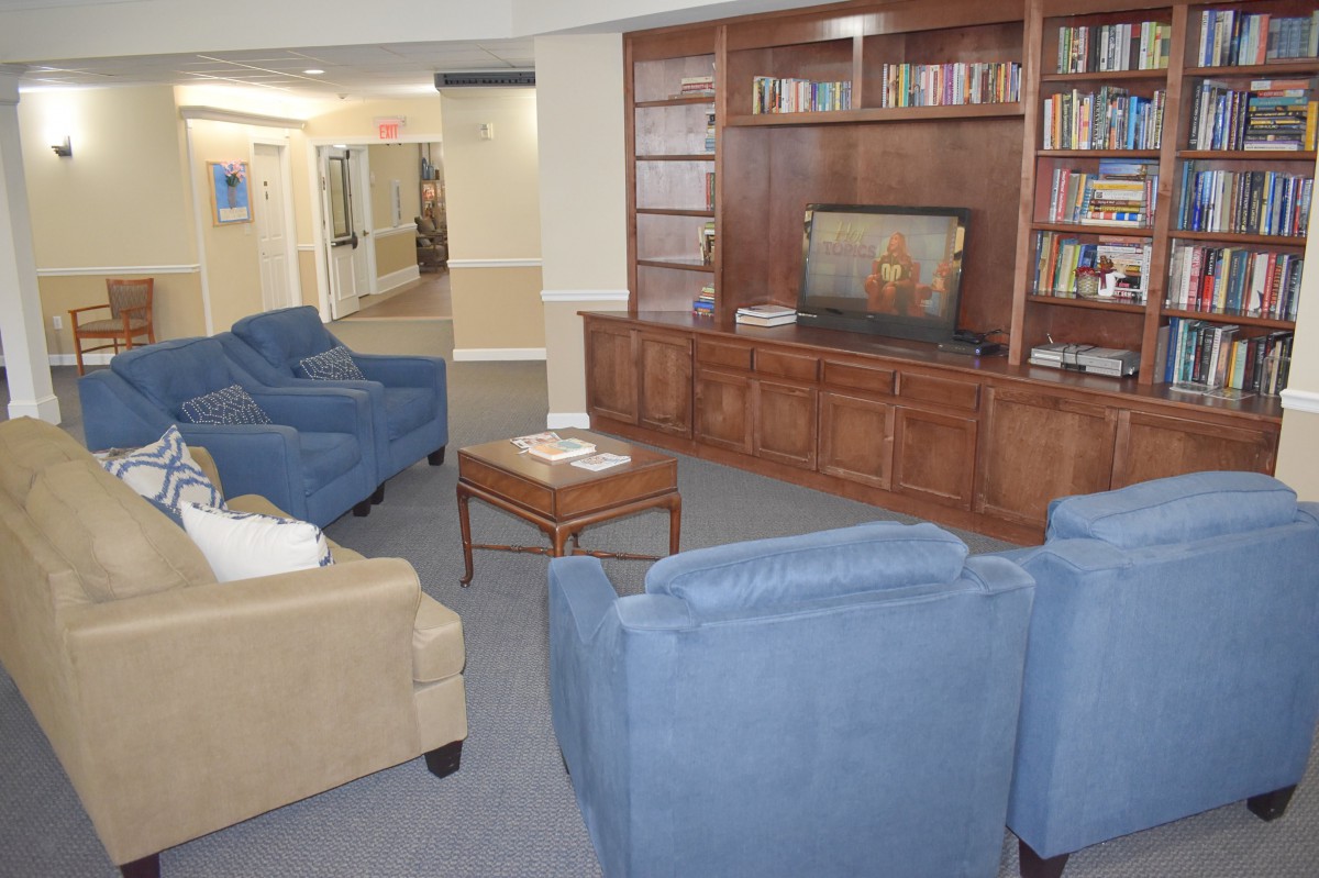 A cozy living room with comfortable seating, a wooden bookshelf, and a television.