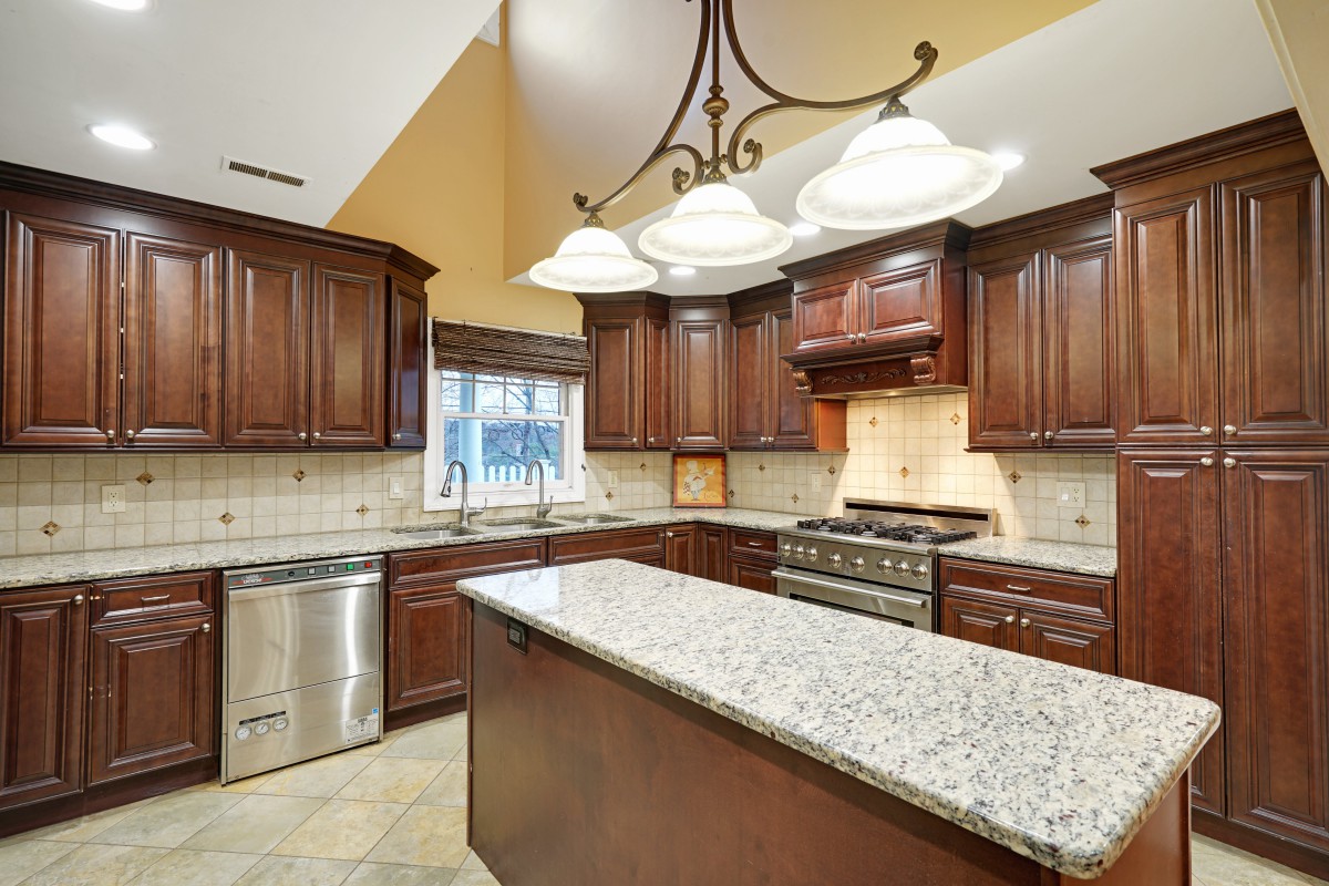 A spacious kitchen with wooden cabinets, a granite island, and modern appliances.