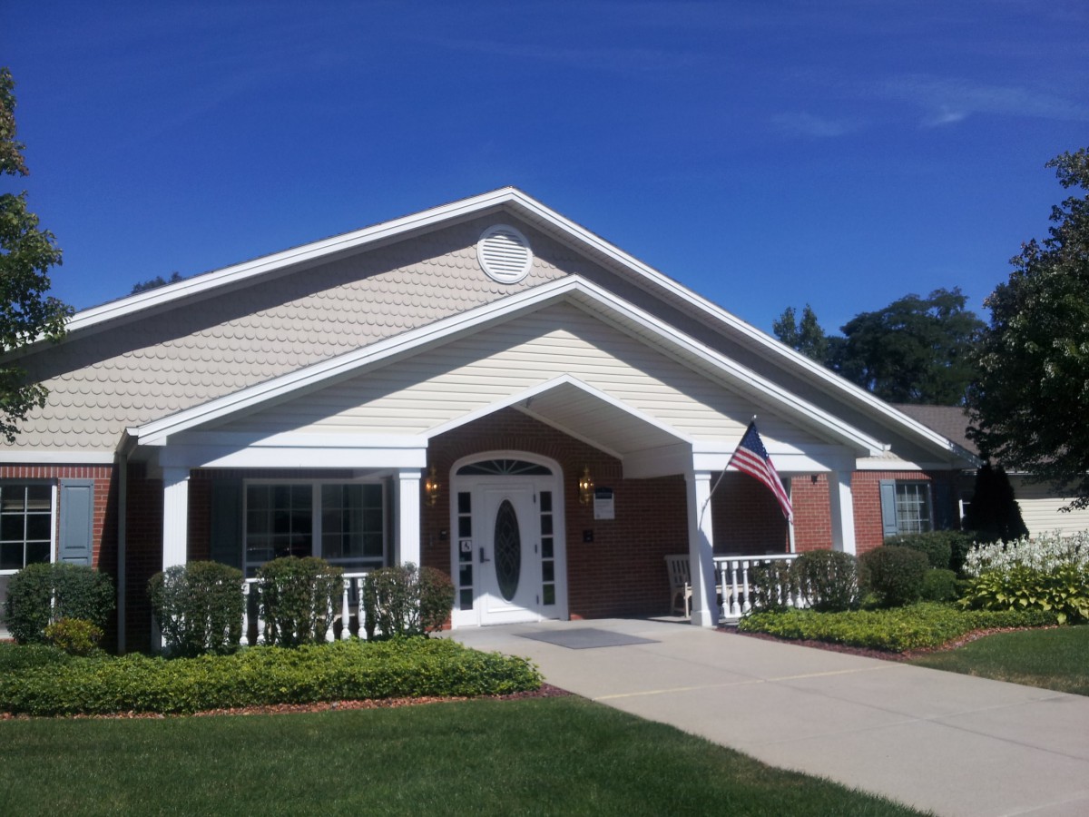 A suburban house with a neatly maintained lawn and a small American flag displayed by the entrance on a sunny day.