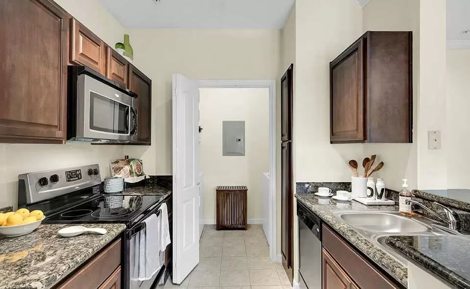A modern galley-style kitchen with dark wood cabinets and stainless steel appliances.