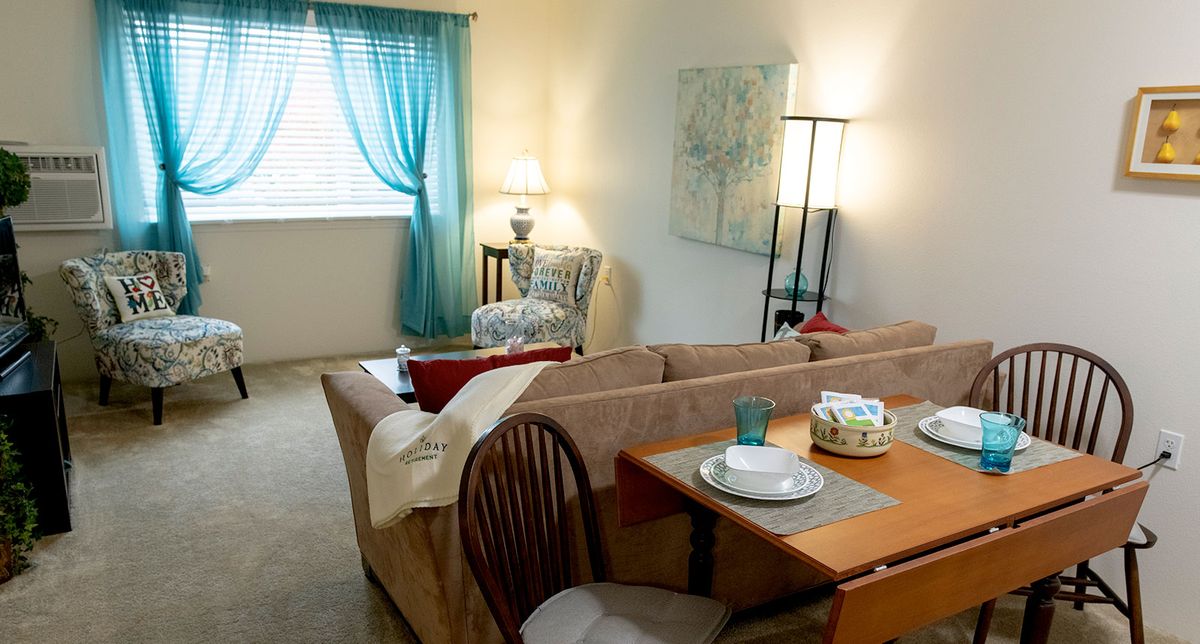 Cozy living room with dining area, featuring a comfortable couch and a set table.