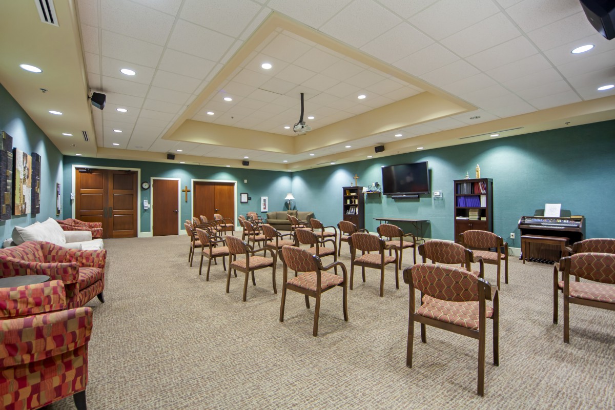 A spacious waiting room with neatly arranged chairs and a television on the wall.