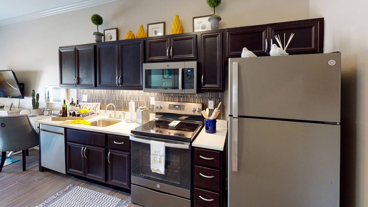 A modern kitchen with dark cabinets and stainless steel appliances.