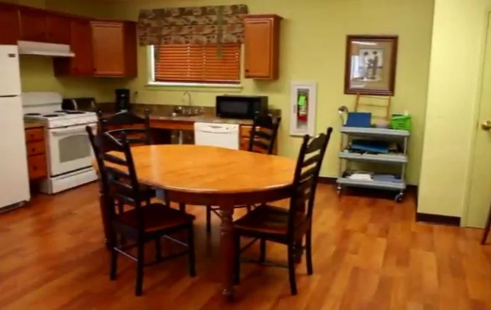 A cozy kitchen with a wooden dining table and chairs, featuring modern appliances and cabinetry.