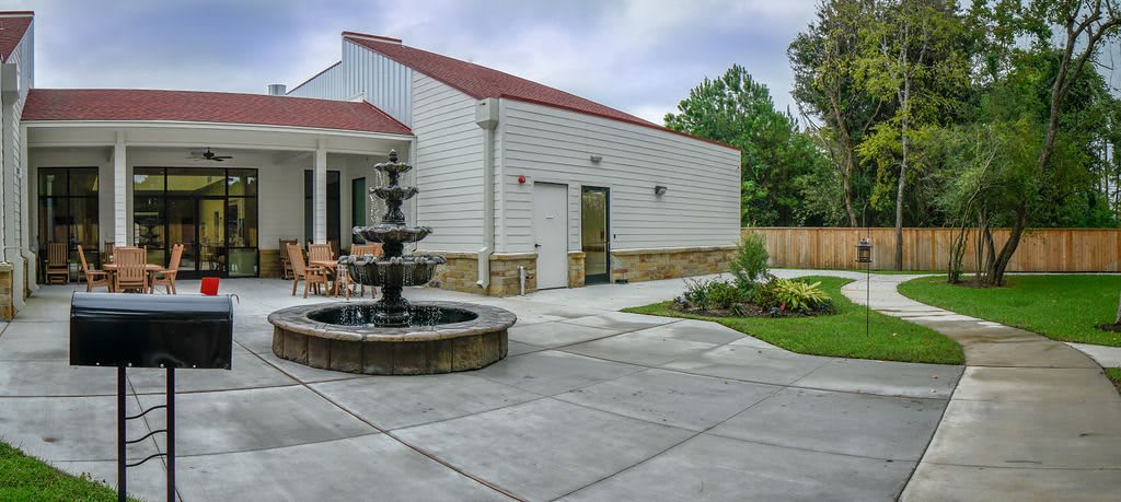 A modern house with a landscaped yard featuring a patio and a fountain.
