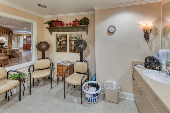 A cozy salon waiting area with chairs, hair dryers, and charming wall decorations.