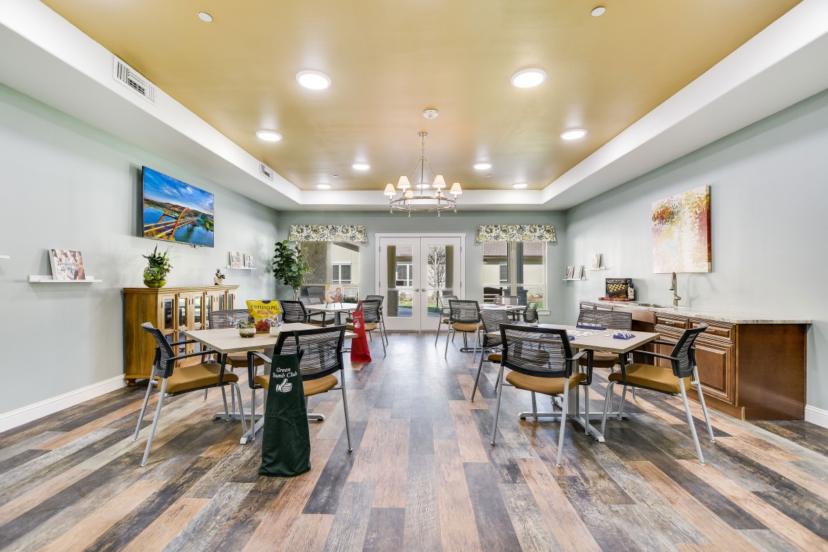 A modern dining room with neatly arranged tables and chairs, featuring elegant lighting and stylish decor.