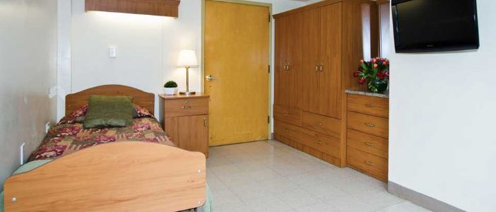 A tidy bedroom with wooden furniture, including a wardrobe and bedside table.