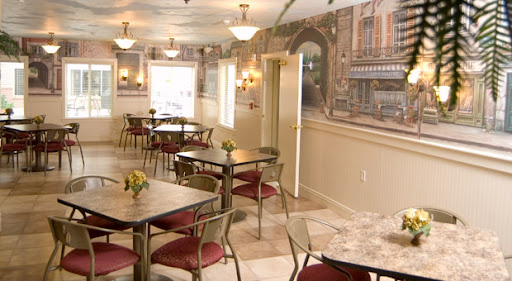 A cozy dining area featuring tables and chairs, enhanced by decorative wallpaper and bright lighting.