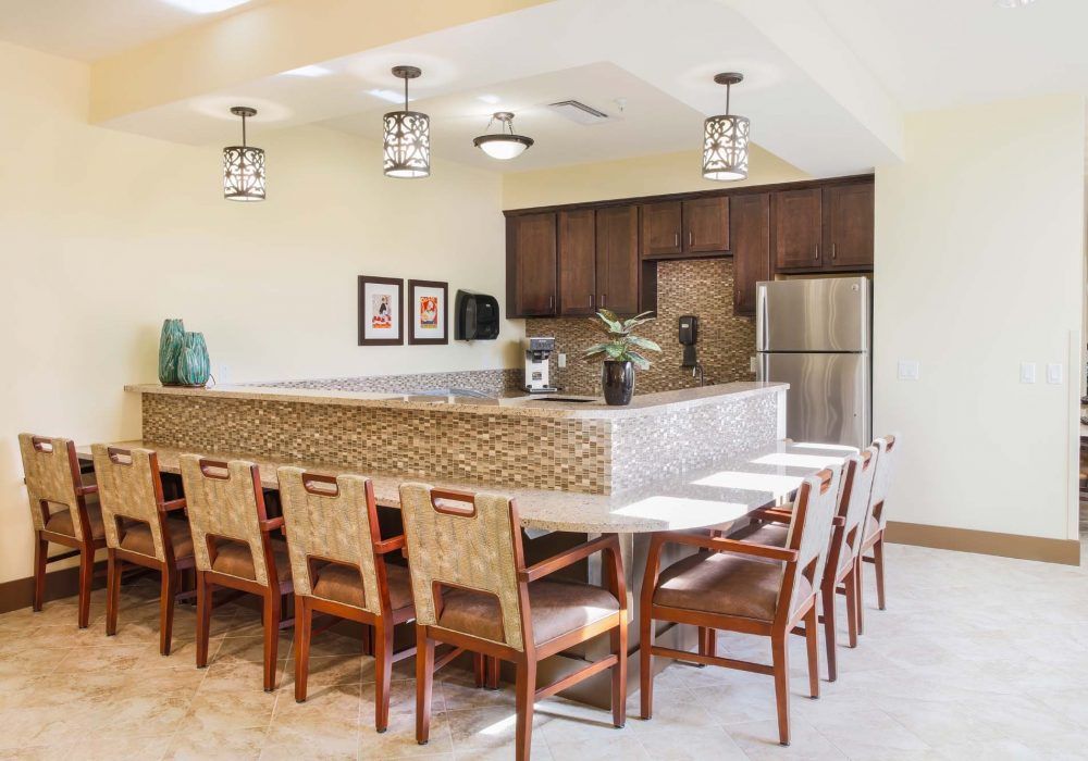 A modern kitchen and dining area with wooden cabinetry, stainless steel appliances, and seating for eight.
