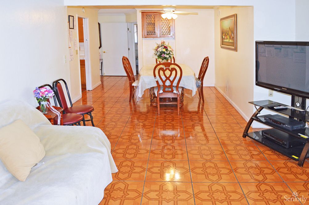 A cozy living room featuring a tiled floor and a dining area with elegant chairs.