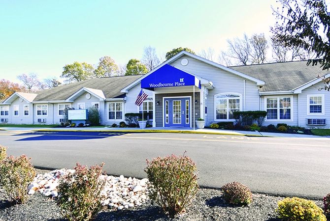 A healthcare clinic building with a blue sign and well-maintained landscaping.