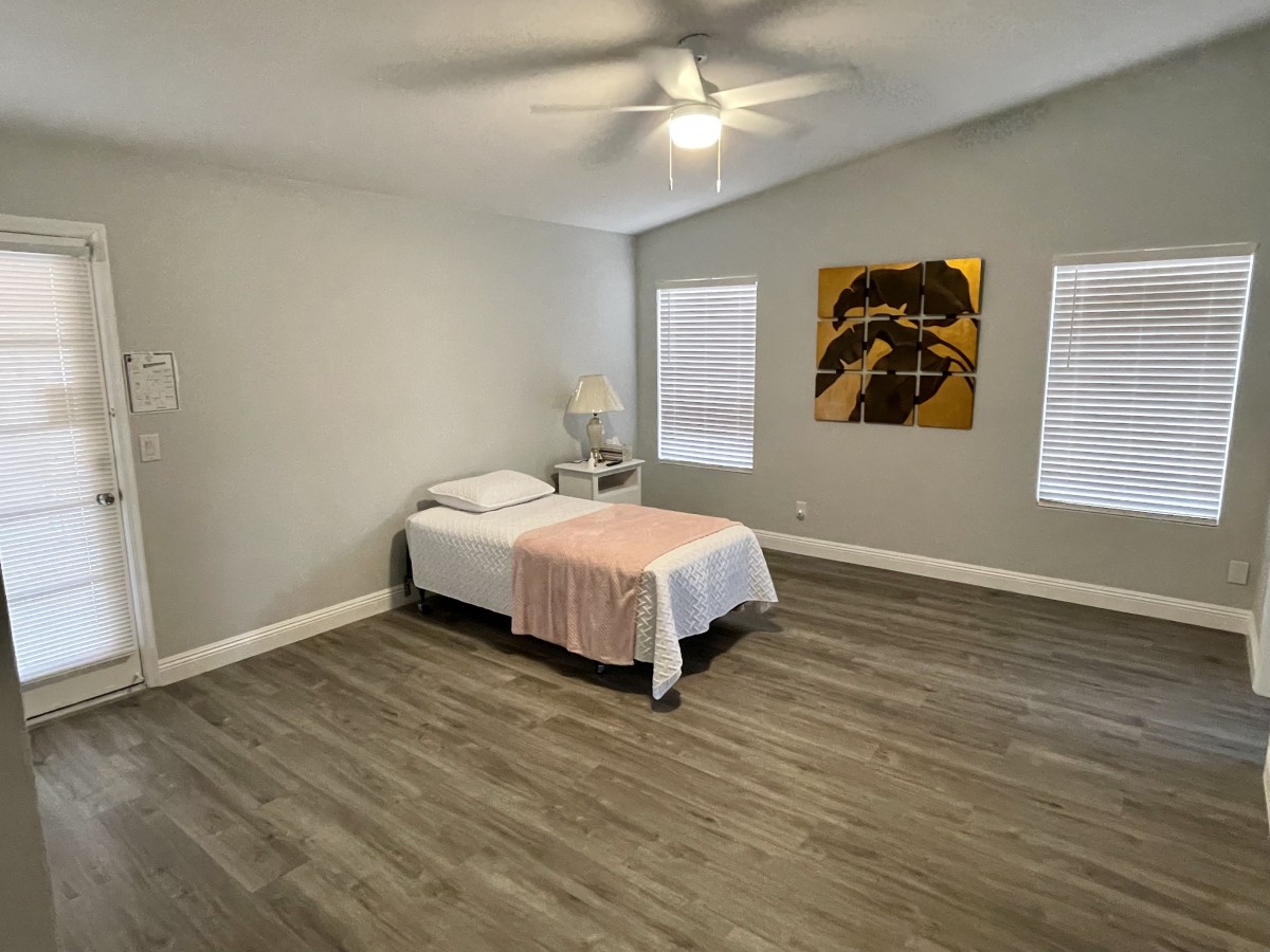 A minimalist bedroom with a single bed, wooden floors, and decorative wall art.
