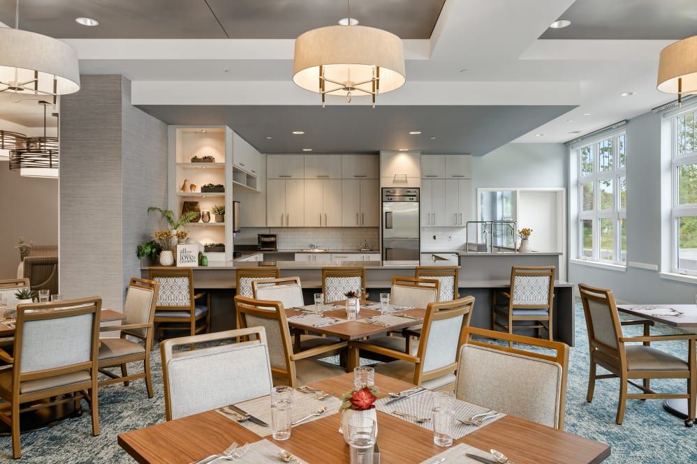 A modern kitchen and dining area with wooden tables and chairs, featuring sleek cabinetry and contemporary lighting.