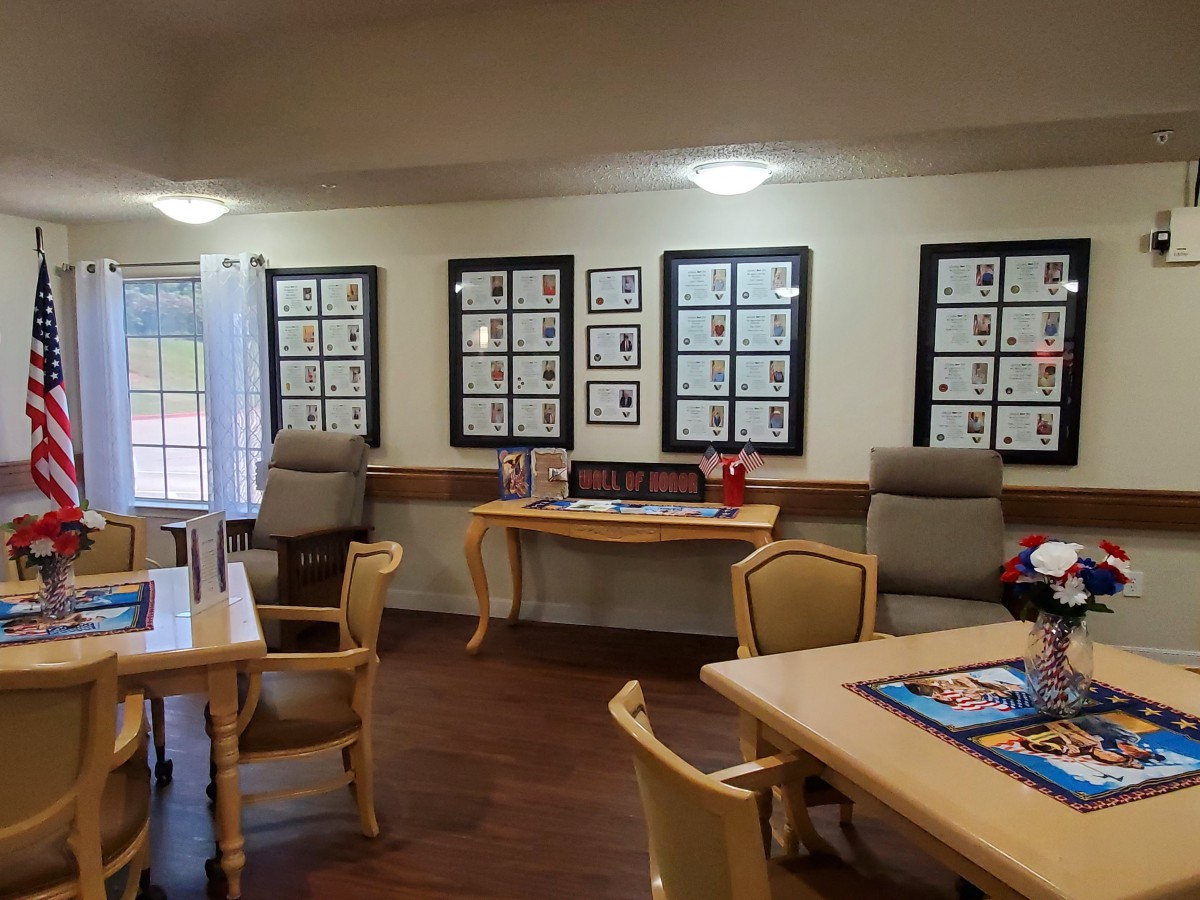 A well-lit room with tables and chairs, decorated with framed artwork on the walls.