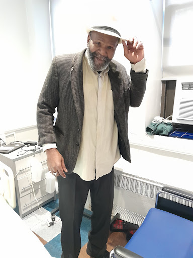 A cheerful man in a casual outfit, tipping his hat.