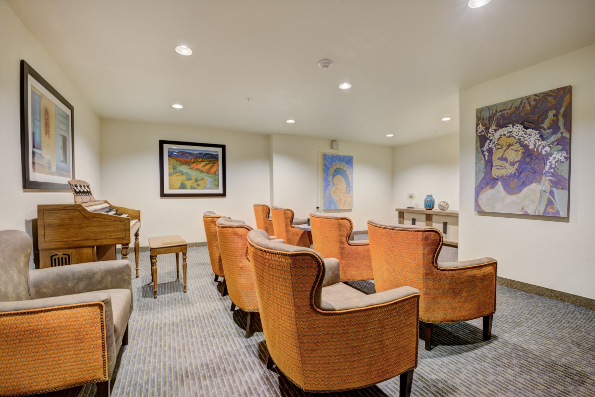 An indoor seating area with a row of orange chairs and artwork on the walls.