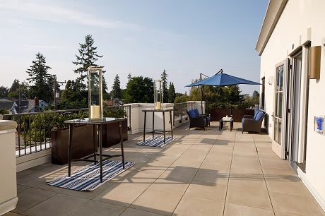 A sunny patio area with tables, chairs, and an umbrella.