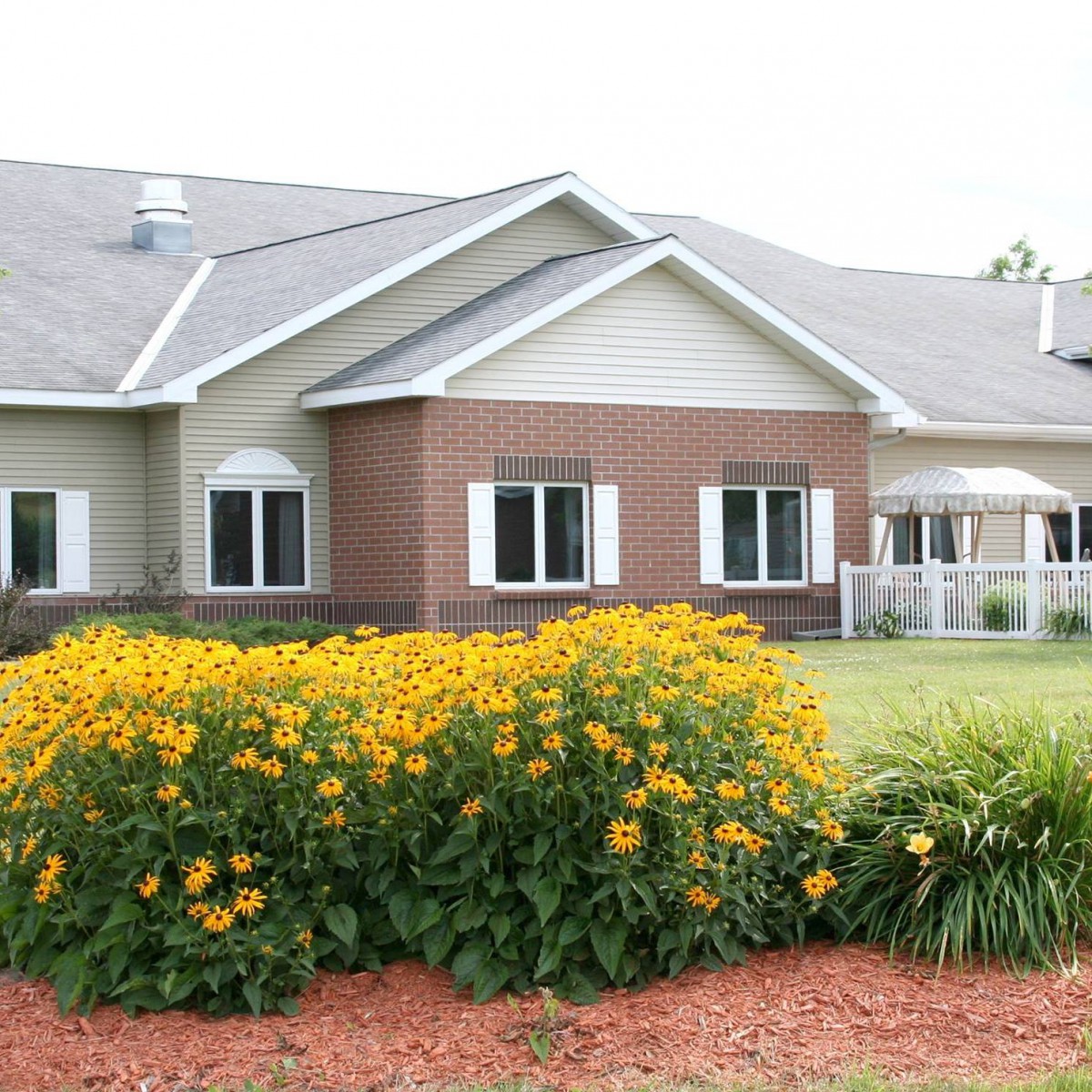 A suburban house with a well-maintained garden and blooming flowers in the foreground.
