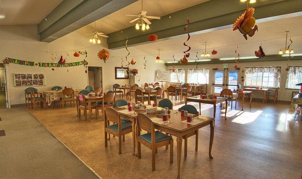 A cozy dining room with decorated tables and ceiling fans.