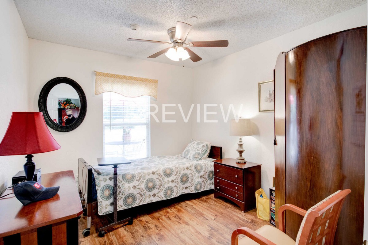 A cozy bedroom with a single bed, wooden furniture, and a ceiling fan.