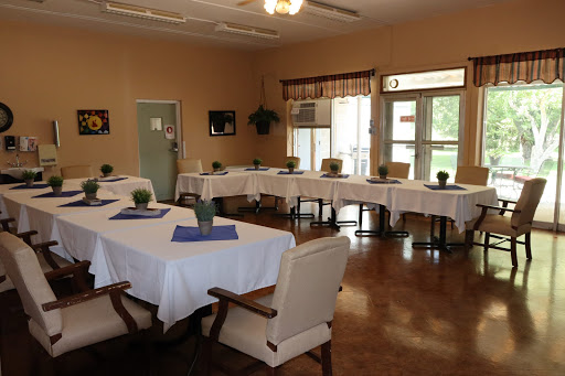A spacious dining area with neatly arranged tables, each topped with a small plant, inviting a comfortable atmosphere.