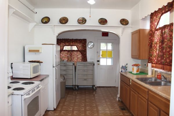 A traditional kitchen with wooden cabinets, a stove, and a microwave, featuring decorative plates on the wall.