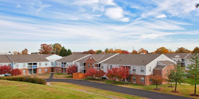 A suburban apartment complex surrounded by colorful autumn trees under a clear blue sky.