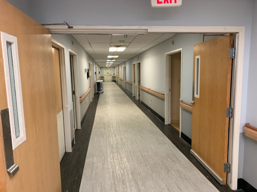 A quiet hospital hallway with doors on either side, leading to patient rooms.