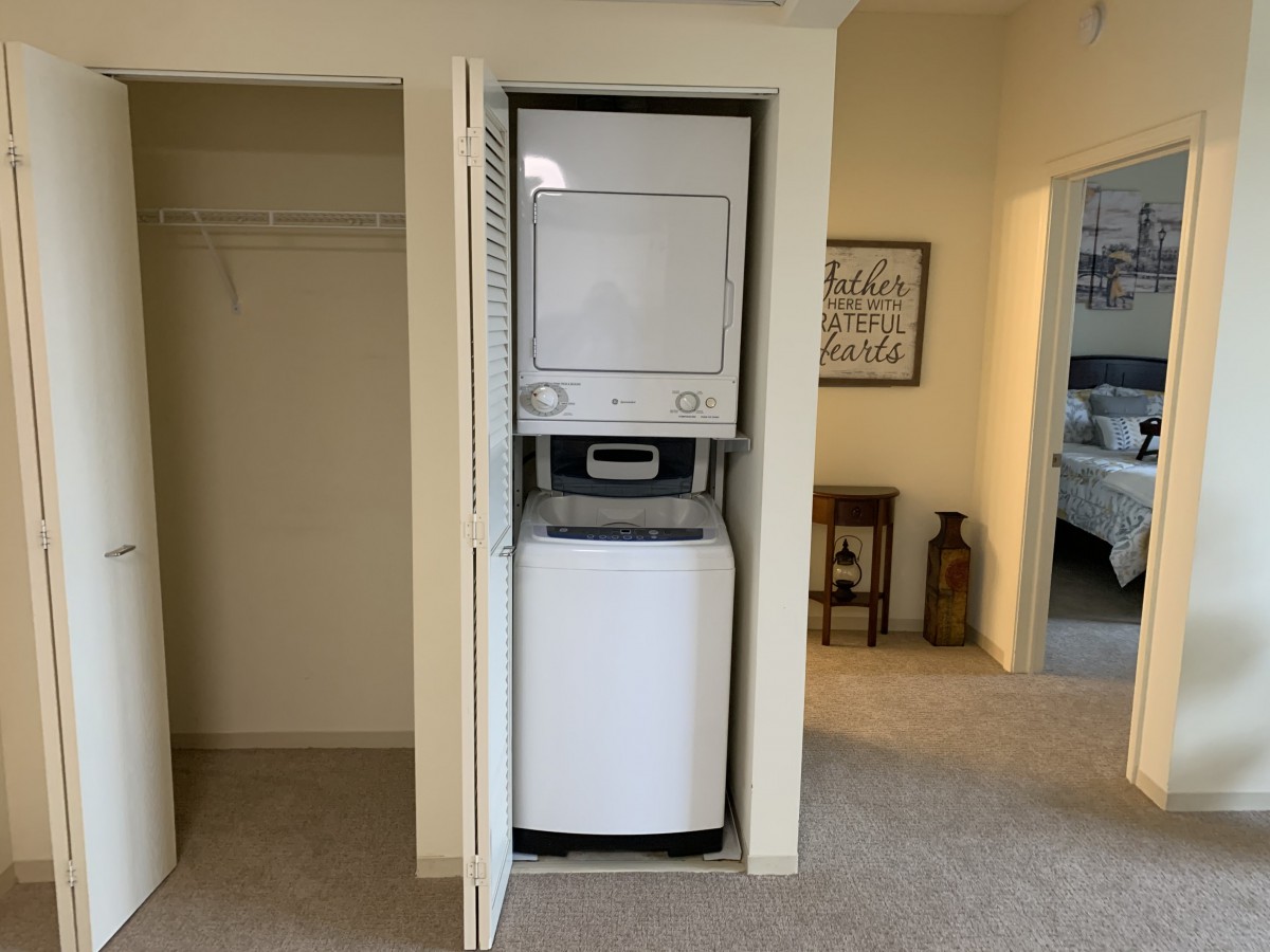 Compact stacked washer and dryer unit inside a small closet space.