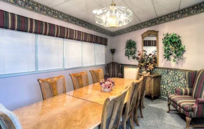 A well-decorated dining room featuring a long wooden table, multiple chairs, and a chandelier.