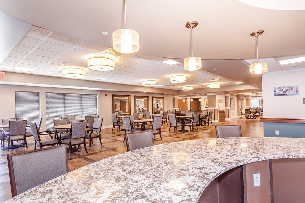 A modern dining area with tables and chairs, illuminated by elegant lighting fixtures.