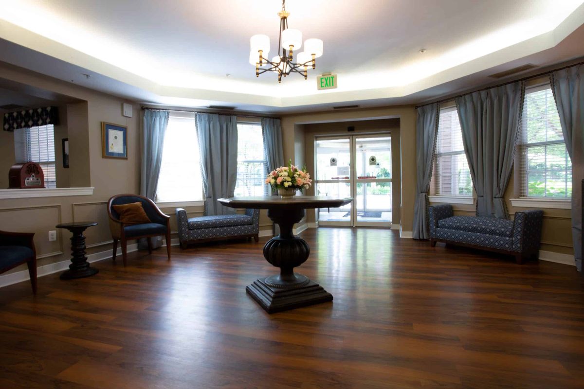 A well-lit living room with elegant furnishings, featuring a central table and chandelier.