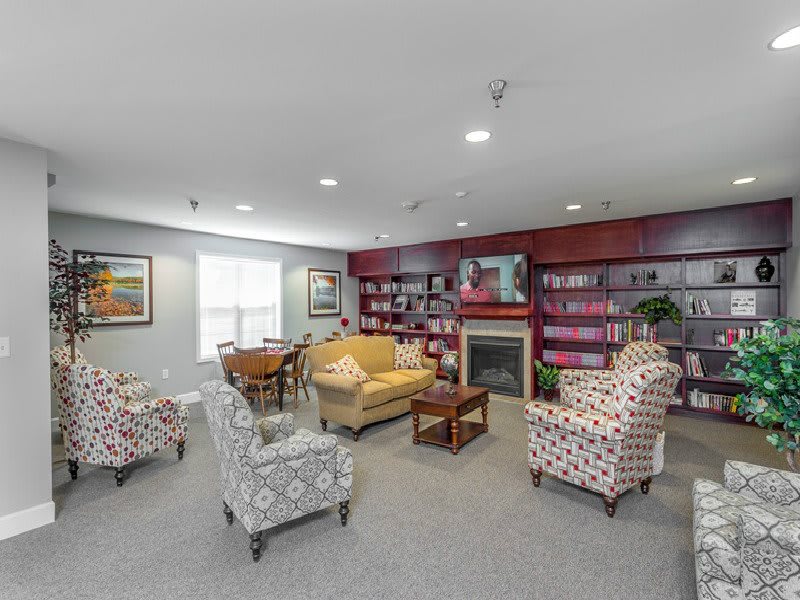 A cozy living room with patterned chairs, a sofa, bookshelves, and a fireplace.