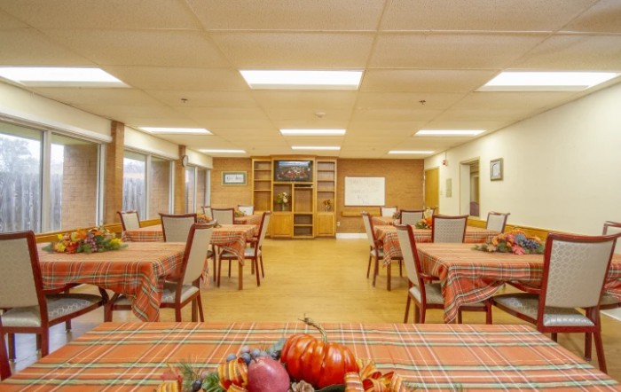 A spacious dining area with tables and chairs neatly arranged, featuring colorful tablecloths and decorative items.