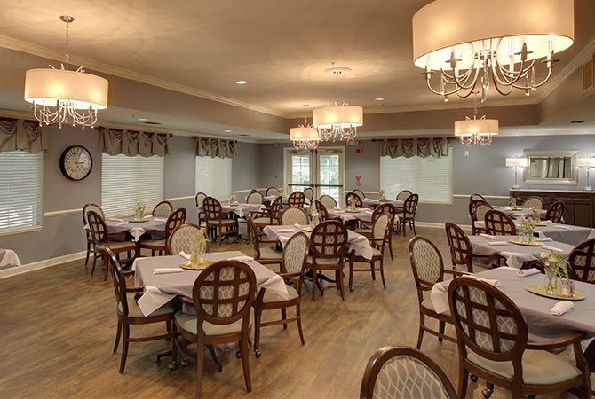 An elegant dining room with multiple tables and chandeliers.